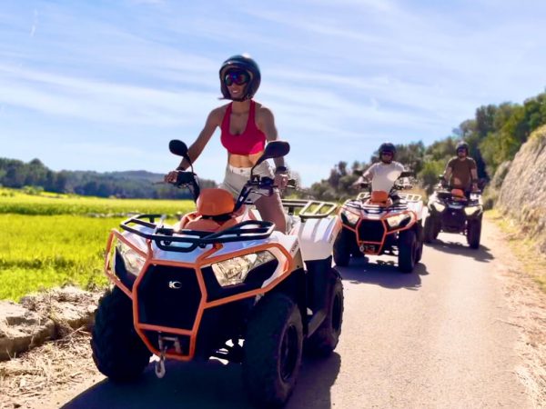 Drei Personen fahren bei Sonnenschein auf Quads durch Mallorcas grüne Landschaft quad mallorca